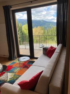 a living room with a couch and a large window at Apartmán Brčálník Šumavské Stráně in Hojsova Stráž