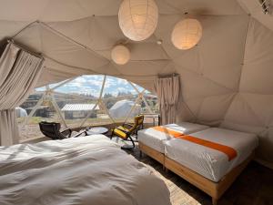 two beds in a room with a tent at 里山グランピングむすび in Mizunami