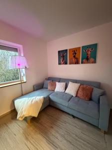a living room with a blue couch and a window at Orfű Hillside in Orfű