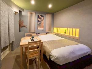 a bedroom with a bed and a desk and a window at HOTEL 壮-soh-shibuya in Tokyo