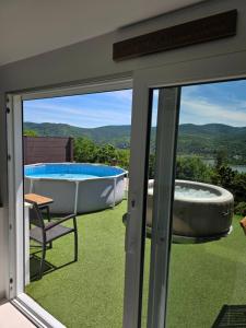 a sliding glass door with a tub and a chair at Dunakanyar View Apartman in Nagymaros