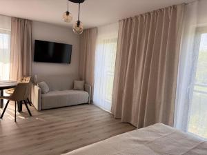 a living room with a couch and a tv on the wall at Albian Apartamenty in Jantar +85 photos