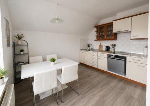a kitchen with white cabinets and a white table and chairs at Apartment Čebelica in Lesce