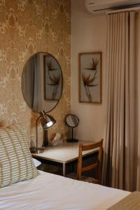 a bedroom with a bed and a desk with a mirror at Stellenbosch Farm Cottage with Mountain Views in Stellenbosch
