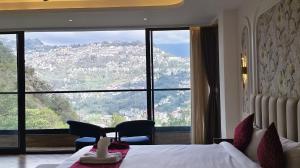 a bedroom with a large window with a mountain view at The Yasa Hotel In Gangtok in Gangtok