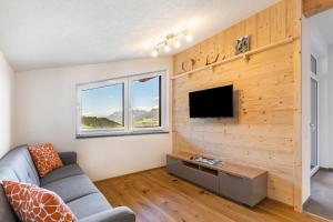 a living room with a couch and a tv on a wall at Ferienwohnung Grubgut in Taxenbach