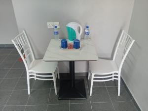 a white table with three chairs and drinks on it at GP StayIn in Lunas