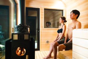 a man and a woman sitting on a couch in front of a stove at 郷音 ～G.O.A.T～ in Tsuru  +31 photos