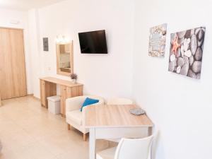 a living room with a table and a tv on a wall at Porfyris Studios and Apartments in Karpathos