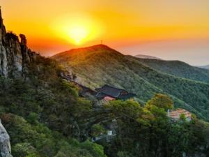 a sunset on a mountain with a cross on a hill at Namhae eunmorae pension in Namhae