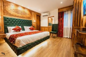 a bedroom with a large bed with a green headboard at Hotel Hamza in Srinagar