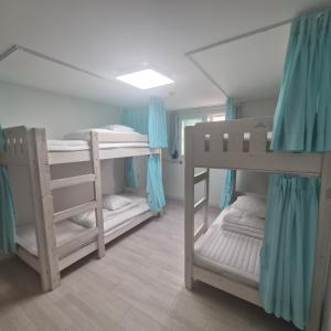 two bunk beds in a room with blue curtains at DreamTrip Guesthouse in Incheon