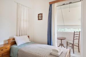 a bedroom with a bed and a chair and a window at Kyma Arch House in Porto Heli