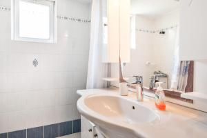 a white bathroom with a sink and a mirror at Kyma Arch House in Porto Heli +16 photos