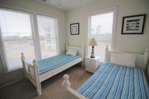 two beds in a bedroom with two windows at Hamilton Cay at Bermuda Bay by Kees Vacations in Kill Devil Hills