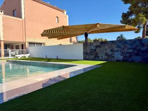 a backyard with a swimming pool and a wooden umbrella at VILLA RINCON DEL BUITRE in Moratalla