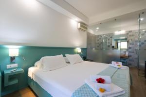 una camera da letto con un grande letto bianco con due asciugamani di Resort Sciabache a Zambrone Altre 35 foto