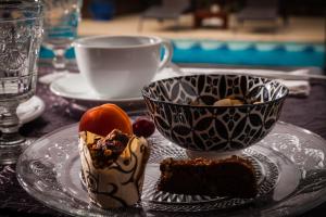 une assiette avec un morceau de gâteau et une tasse de café dans l'établissement La Bergerie Du Cap, au Cap d'Agde