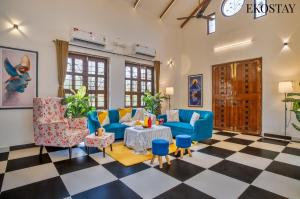 a living room with blue furniture and a checkered floor at EKOSTAY - Mount Emerald Villa in Alibaug