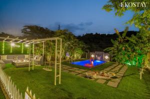 a backyard with a swing and a pool at night at EKOSTAY - Mount Emerald Villa in Alibaug