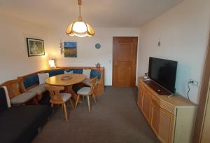 a living room with a couch and a table and a television at Landhaus Rieder in Mittersill