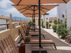 a row of benches with an umbrella on a balcony at Seda Residences in Granada