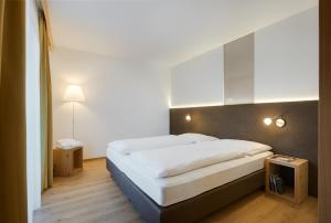 a bedroom with a large white bed and two tables at Hotel Tirolerhof in Rodengo