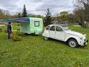 a man standing next to a trailer and a car at Le cocon de Lili et de Patrick in Draveil