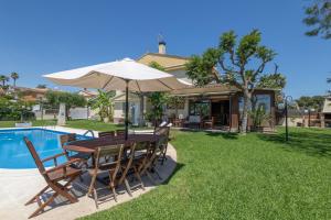 a table and chairs with an umbrella next to a pool at Villa las Terrenas in Calafell