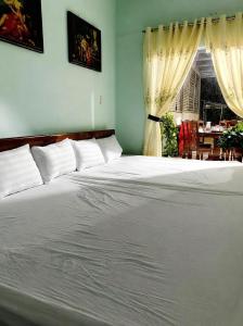 a bedroom with a large white bed with curtains at Cali Homestay Tây Ninh in Tây Ninh