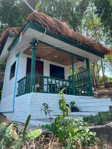 a small white house with a thatch roof at Benny monkey house in Rayong