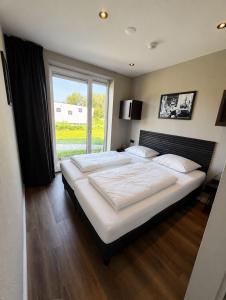 a bedroom with a large bed with a large window at Beach House 314 in Hindeloopen +12 photos