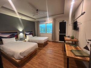 a hotel room with two beds and a window at Eat and Read Hotel in Skardu
