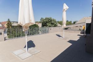two white umbrellas sitting on a patio at Maya Panzio-Rezidencia in Szeged