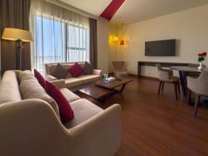 a living room with a couch and a table at Carnelian Muscat - Airport Hotel in Muscat
