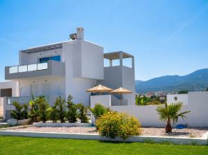 a white house with umbrellas in front of it at Lilu Villa 2 with Private Pool and Seaview in Tigaki