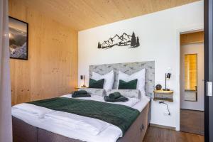 a bedroom with a large bed with green and white pillows at Ferienhaus Auerberg Sweet in Stötten am Auerberg