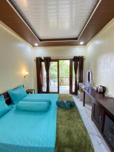 a bedroom with a large blue bed and a desk at Pele's Place Coral Reef Bungalows & Café Maman in Sabang +57 photos