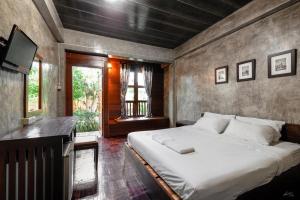 a bedroom with a large bed and a television at Huan Aumpron Resort in Ban Kha Ngam