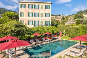 a pool with chairs and umbrellas in front of a building at Villa Rosmarino in Camogli