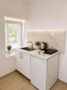 a kitchen with white cabinets and a sink and a window at Apartments Marko in Ohrid +11 photos
