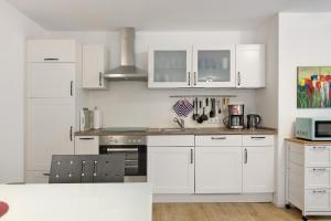 a white kitchen with white cabinets and a sink at Premium Ferienwohnung Dörr in Singen