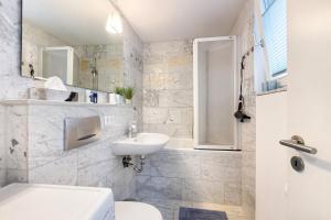 a white bathroom with a sink and a toilet at Premium Ferienwohnung Dörr in Singen +17 photos