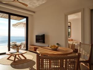 a living room with a table and a view of the ocean at Theros Luxury Suites in Agios Nikolaos