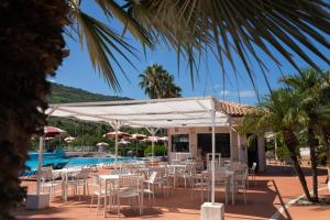 un patio con tavoli e sedie accanto a una piscina di Resort Sciabache a Zambrone