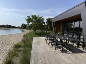 a dining table and chairs on a deck next to a beach at Beach House 314 in Hindeloopen