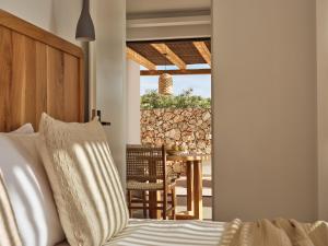 a bedroom with a bed and a table and a wall at Theros Luxury Suites in Agios Nikolaos