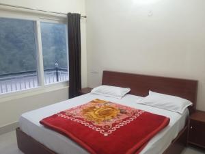 a bed with a red blanket and a window at Tapovan ganga view in Uttarkāshi
