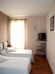 Rúm í herbergi á Logis Hotel L'Occitan 2 étoiles