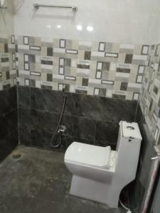 a bathroom with a toilet and a tile wall at Bindwasini Hotel And Party Palace in Bīrganj